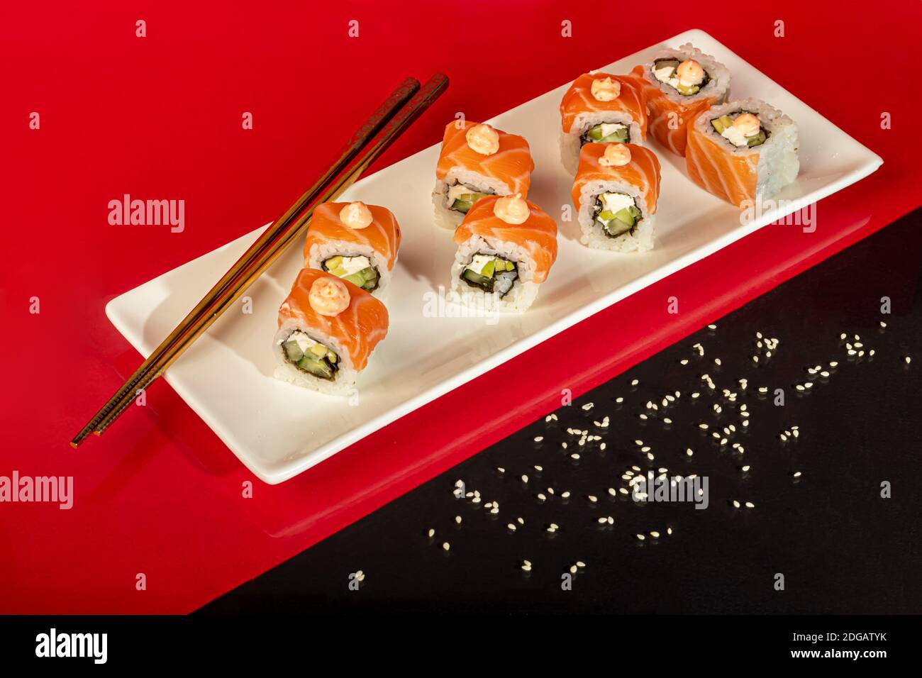 Sushi setzt Nigiri, Uramaki, California, Philadelphia, auf einen weißen Teller. Auf einem roten Hintergrund. Speicherplatz kopieren. Stockfoto