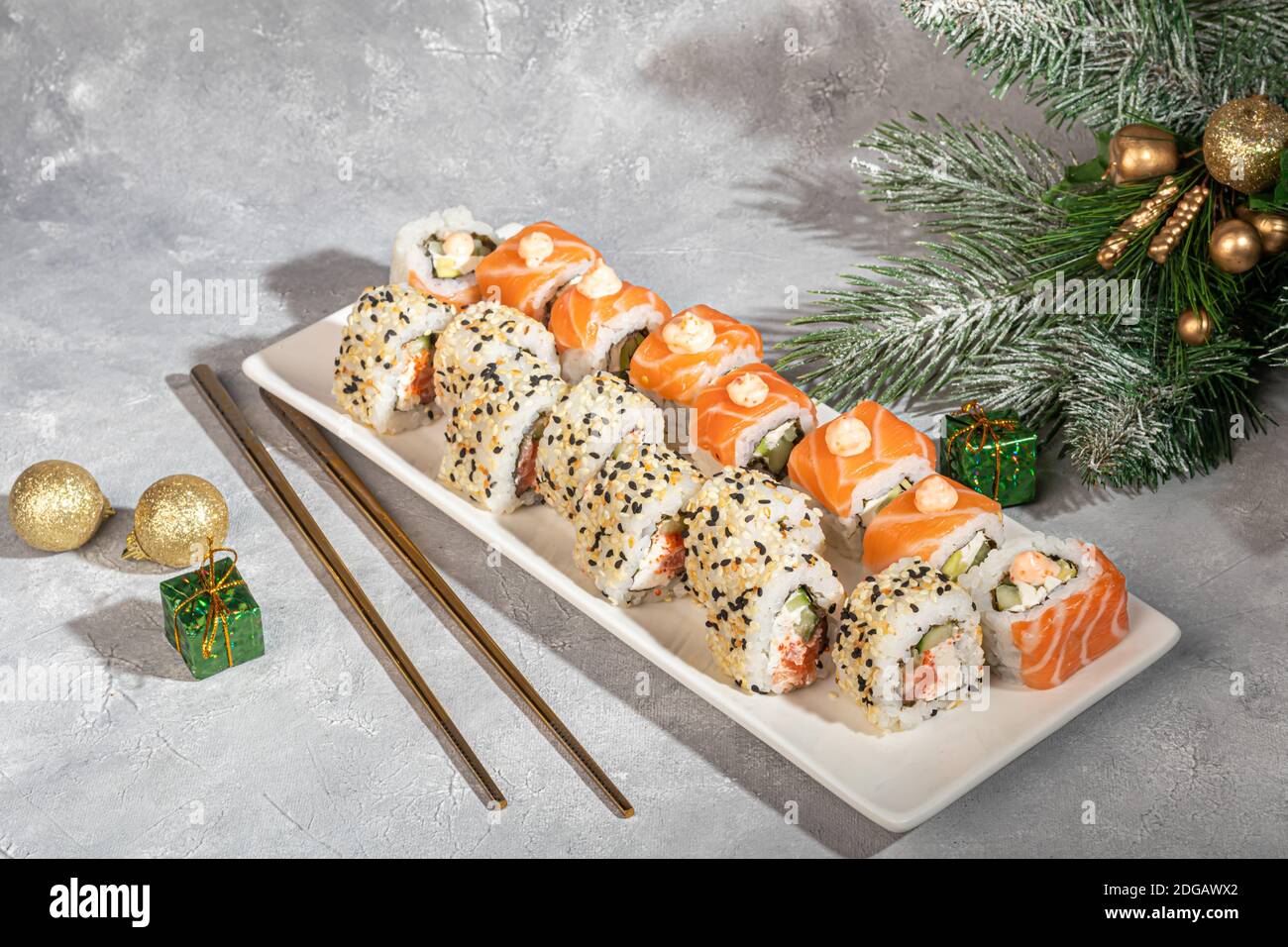 Sushi setzt Uramaki, California, Philadelphia, auf einen weißen Teller. Neujahr und festliches Konzept. Auf einem hellgrauen Hintergrund. Speicherplatz kopieren. Stockfoto