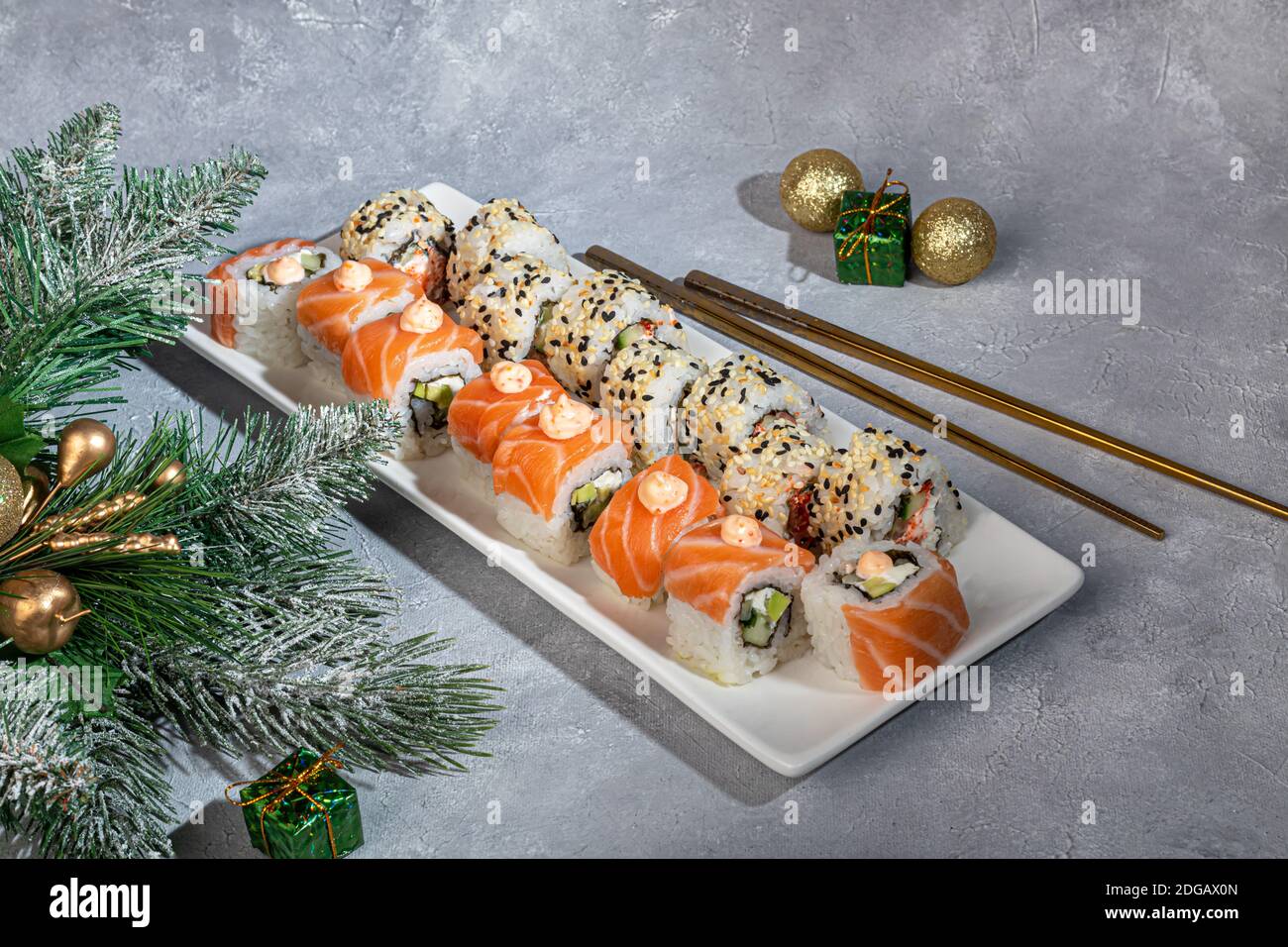 Sushi setzt Uramaki, California, Philadelphia, auf einen weißen Teller. Neujahr und festliches Konzept. Auf einem hellgrauen Hintergrund. Speicherplatz kopieren. Stockfoto