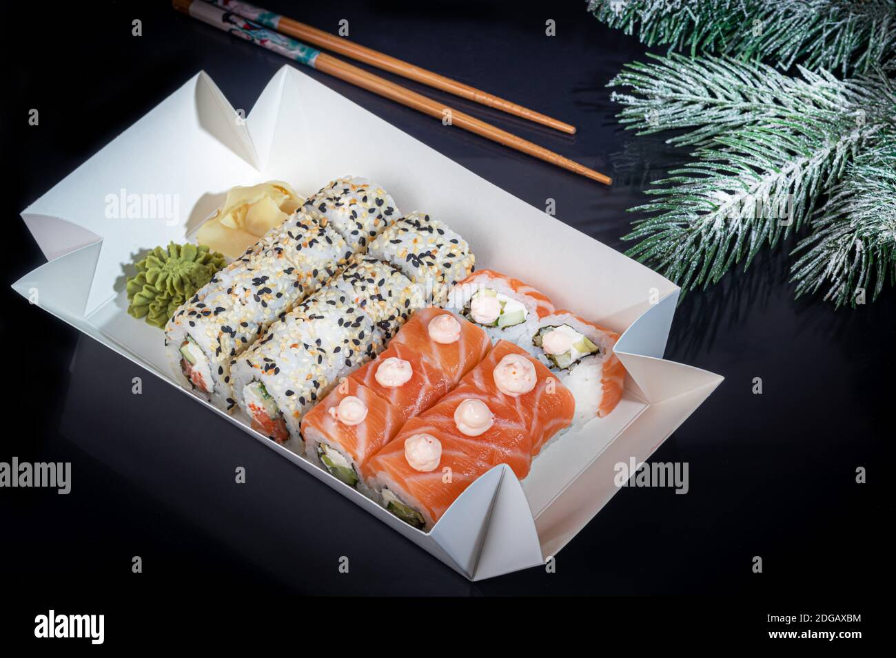 Sushi setzt Uramaki, California, Philadelphia, auf einen weißen Teller. Festliches Neujahrskonzept. Vor einem dunklen reflektierenden Hintergrund. Speicherplatz kopieren Stockfoto