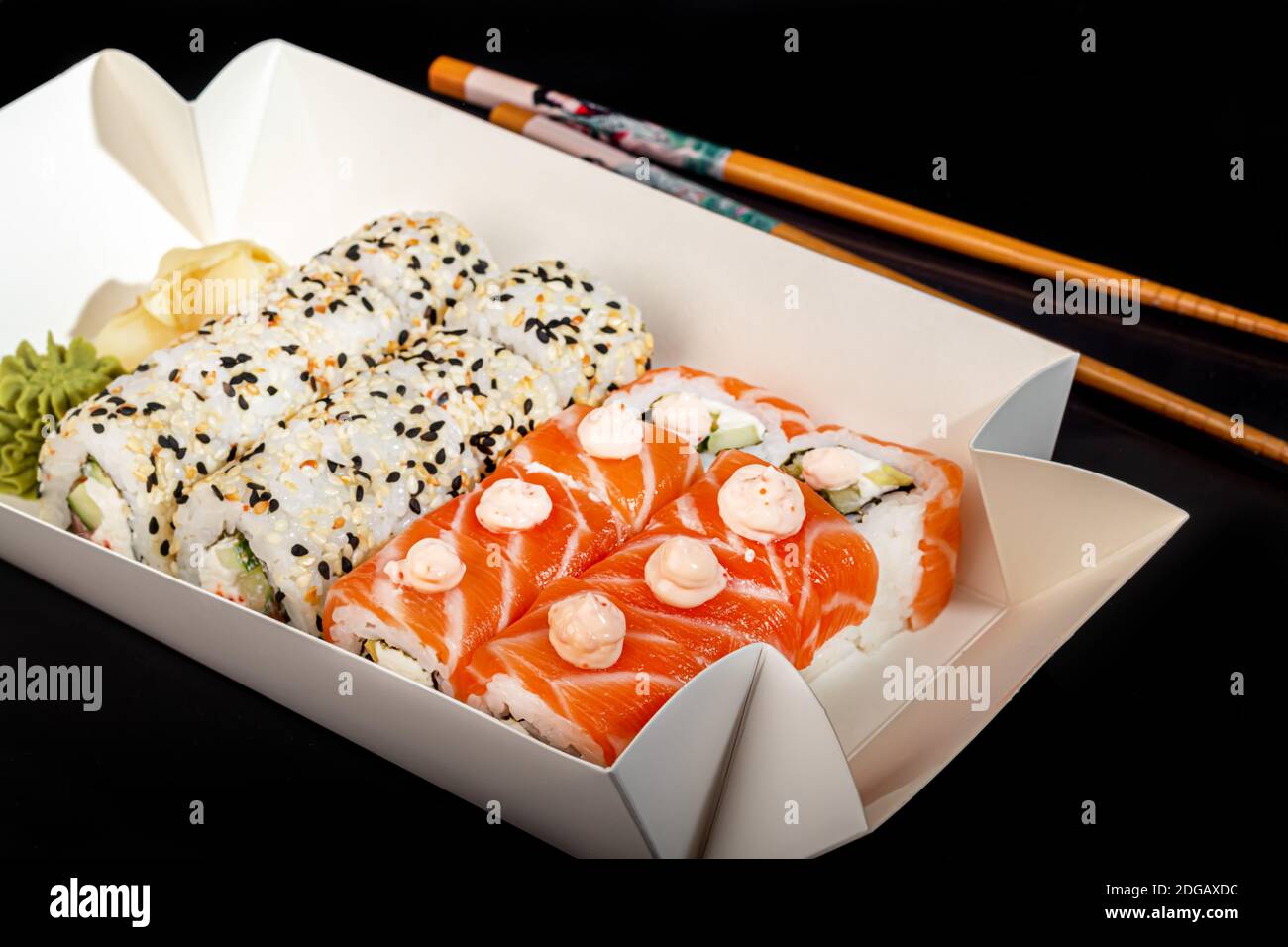 Sushi setzt Uramaki, California, Philadelphia, auf einen weißen Teller. Festliches Neujahrskonzept. Vor einem dunklen reflektierenden Hintergrund. Speicherplatz kopieren Stockfoto