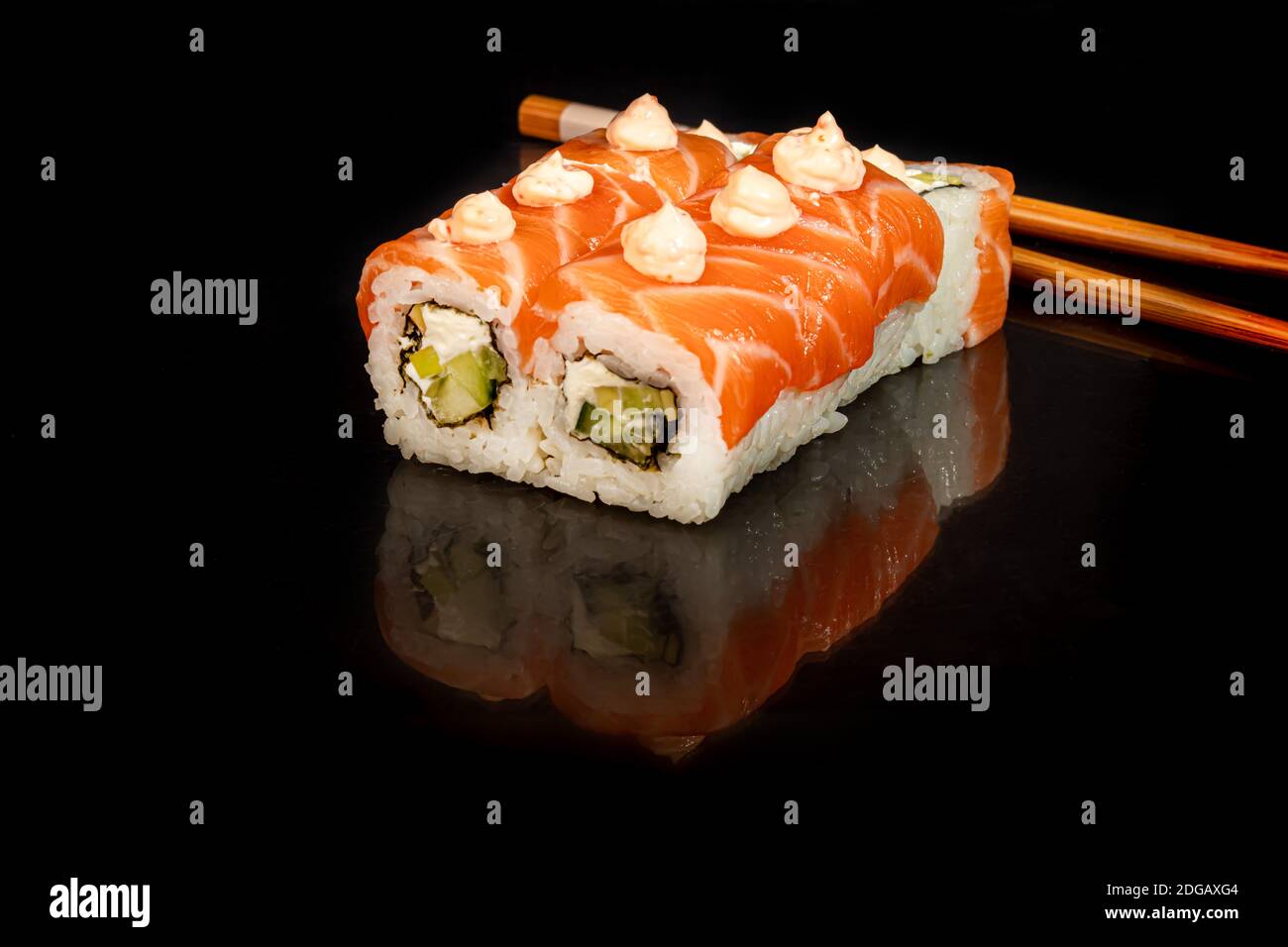Sushi setzt Uramaki, California, Philadelphia, auf einen weißen Teller. Festliches Neujahrskonzept. Vor einem dunklen reflektierenden Hintergrund. Speicherplatz kopieren Stockfoto