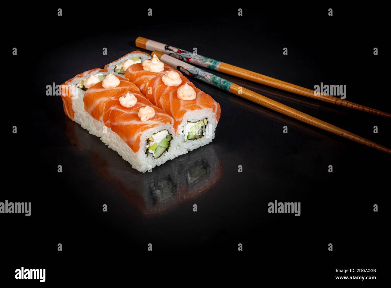 Sushi setzt Uramaki, California, Philadelphia, auf einen weißen Teller. Festliches Neujahrskonzept. Vor einem dunklen reflektierenden Hintergrund. Speicherplatz kopieren Stockfoto