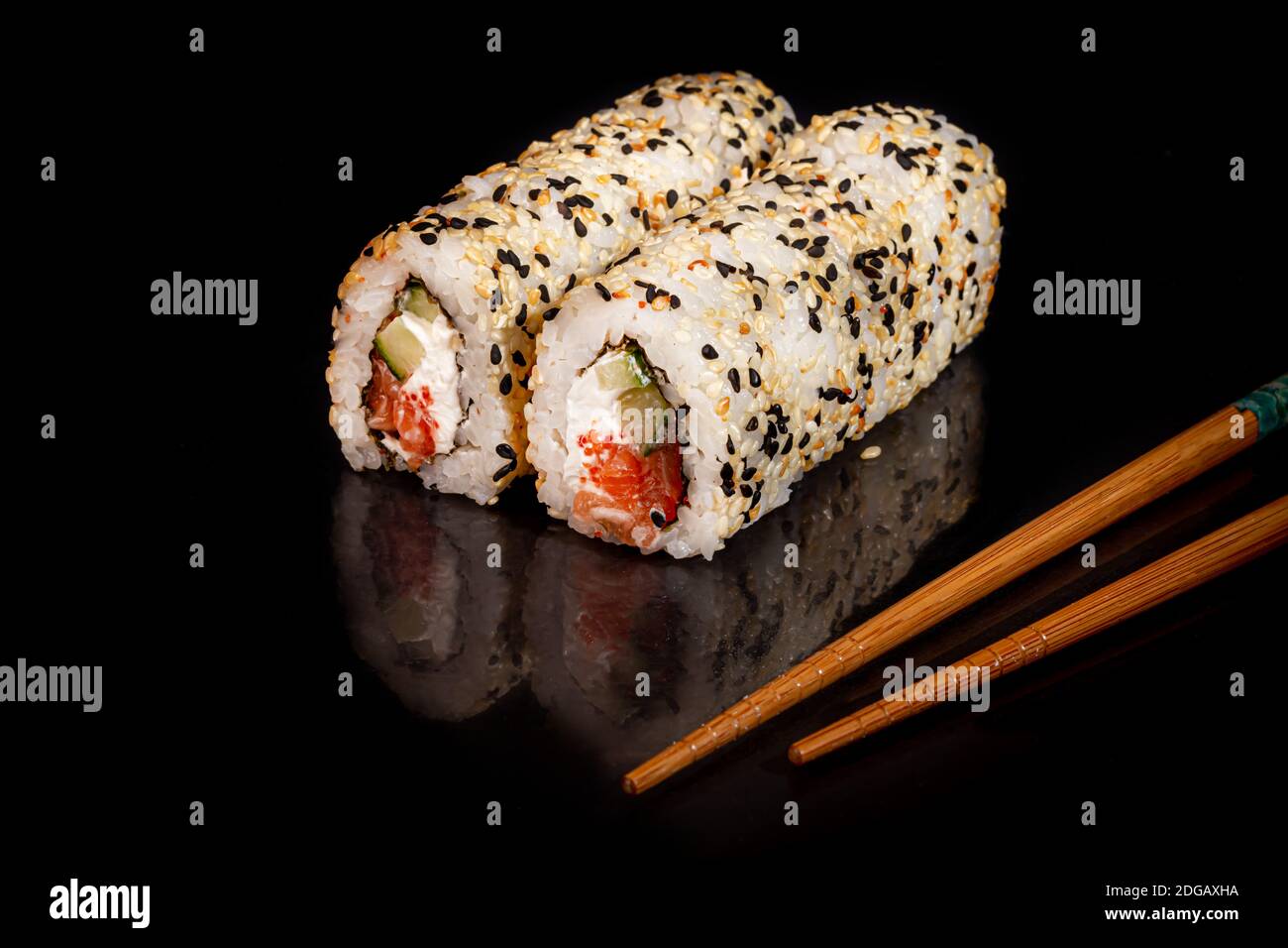 Sushi setzt Uramaki, California, Philadelphia, auf einen weißen Teller. Festliches Neujahrskonzept. Vor einem dunklen reflektierenden Hintergrund. Speicherplatz kopieren Stockfoto