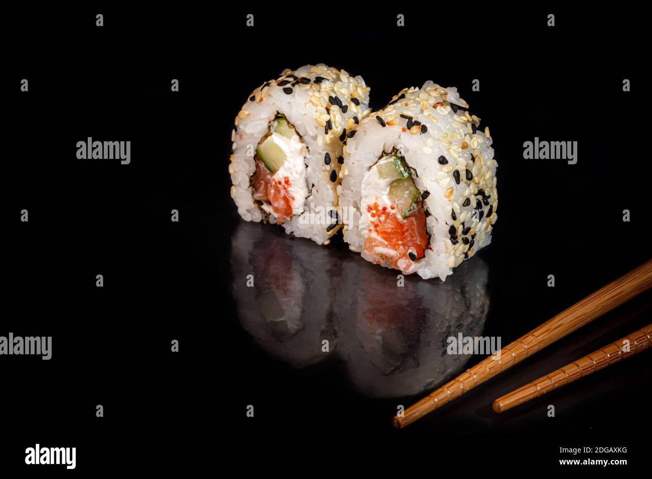 Sushi setzt Uramaki, California, Philadelphia, auf einen weißen Teller. Festliches Neujahrskonzept. Vor einem dunklen reflektierenden Hintergrund. Speicherplatz kopieren Stockfoto
