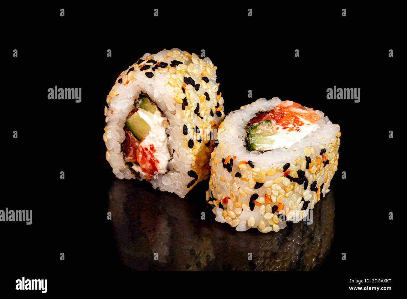 Sushi setzt Uramaki, California, Philadelphia, auf einen weißen Teller. Festliches Neujahrskonzept. Vor einem dunklen reflektierenden Hintergrund. Speicherplatz kopieren Stockfoto
