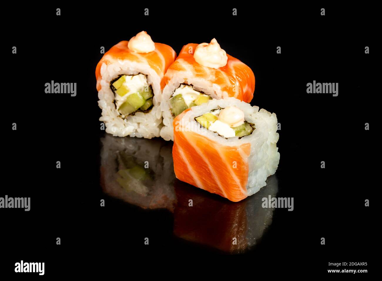 Sushi setzt Uramaki, California, Philadelphia, auf einen weißen Teller. Festliches Neujahrskonzept. Vor einem dunklen reflektierenden Hintergrund. Speicherplatz kopieren Stockfoto