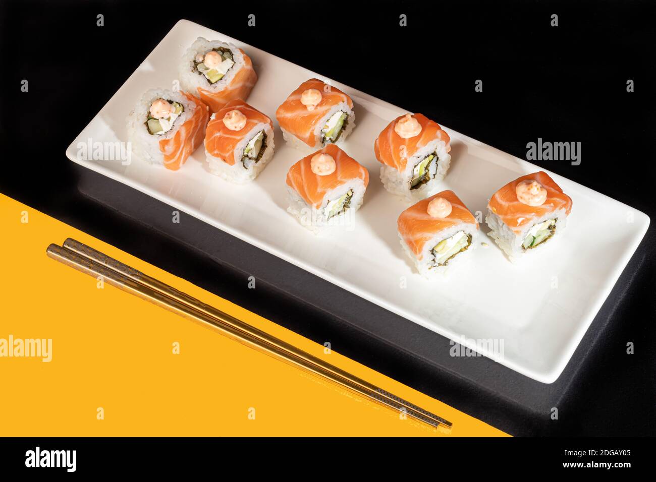 Sushi setzt Uramaki, California, Philadelphia, auf einen weißen Teller. Festliches Neujahrskonzept. Vor einem dunklen reflektierenden Hintergrund. Speicherplatz kopieren Stockfoto