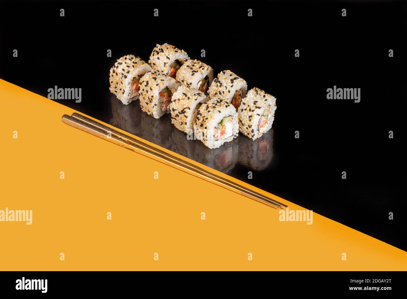 Sushi setzt Uramaki, California, Philadelphia, auf einen weißen Teller. Festliches Neujahrskonzept. Vor einem dunklen reflektierenden Hintergrund. Speicherplatz kopieren Stockfoto