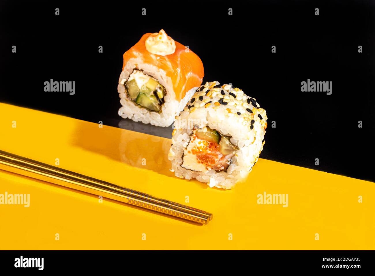 Sushi setzt Uramaki, California, Philadelphia, auf einen weißen Teller. Festliches Neujahrskonzept. Vor einem dunklen reflektierenden Hintergrund. Speicherplatz kopieren Stockfoto