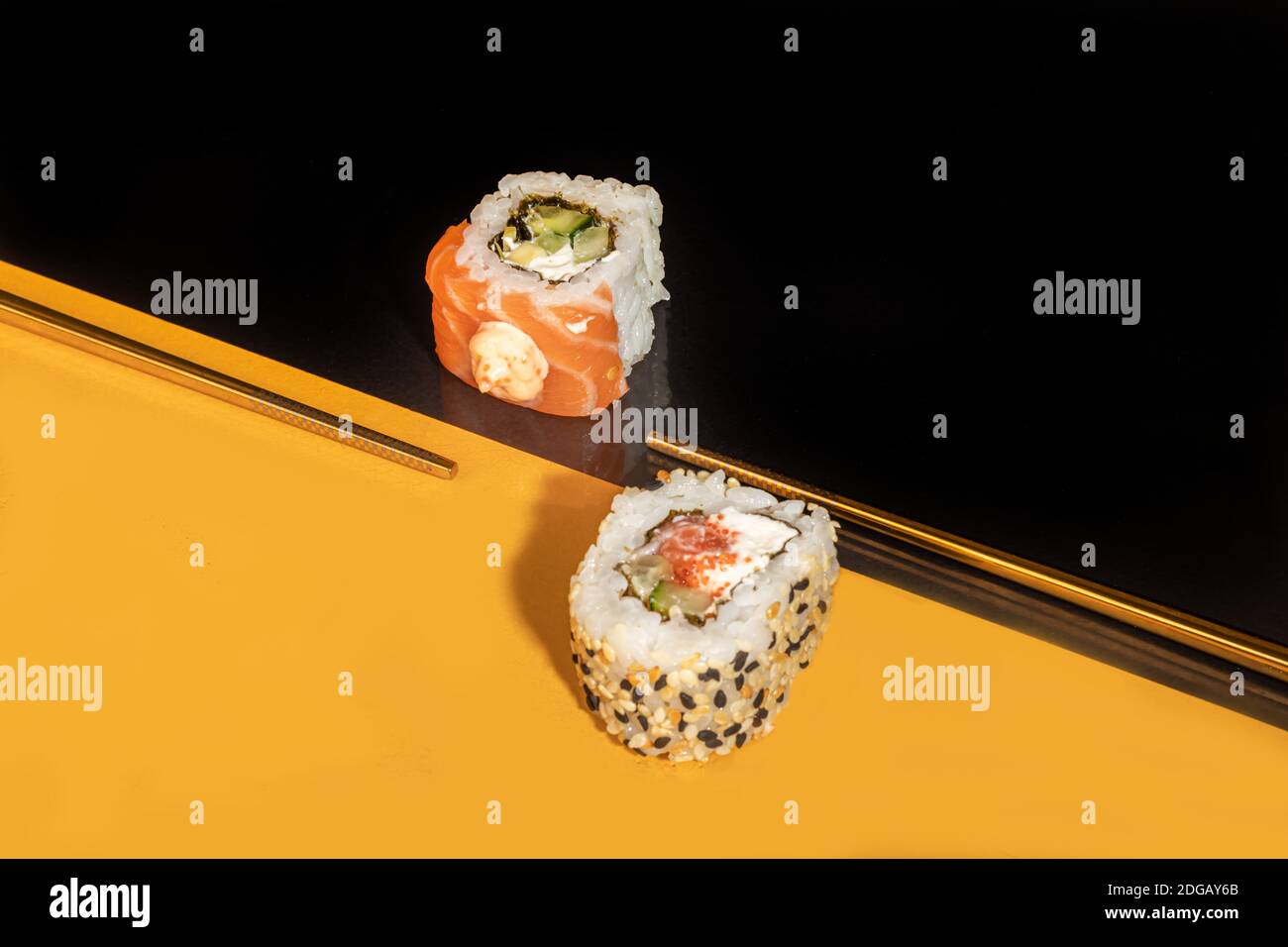 Sushi setzt Uramaki, California, Philadelphia, auf einen weißen Teller. Festliches Neujahrskonzept. Vor einem dunklen reflektierenden Hintergrund. Speicherplatz kopieren Stockfoto