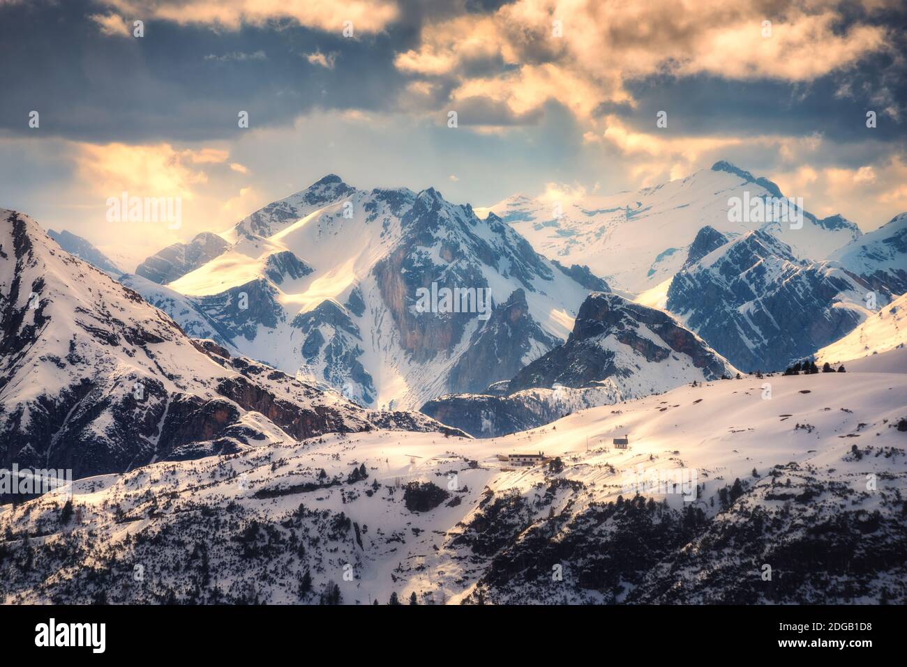 Schneebedeckte Berge werden bei Sonnenuntergang im Winter vom Sonnenstrahl beleuchtet Stockfoto