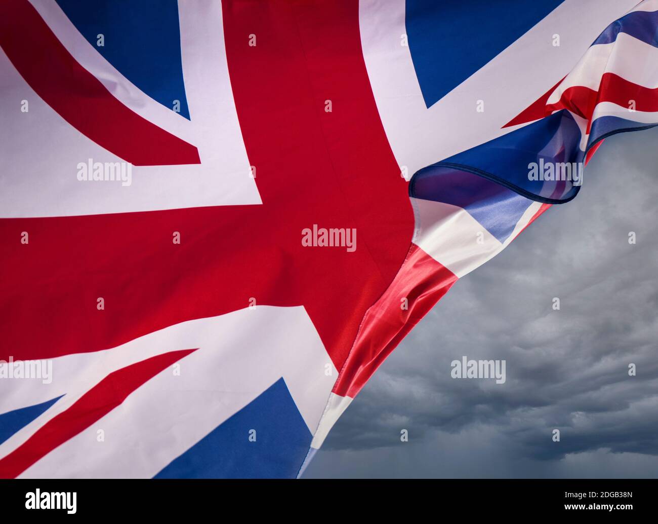EU Brexit-Konzept UK Union Jack Flag fliegt mit einer Brise, die durchweht und einen düsteren Himmel hinter sich als Metapher für Probleme und Konzept für britische Grenzen aufdeckt... Stockfoto