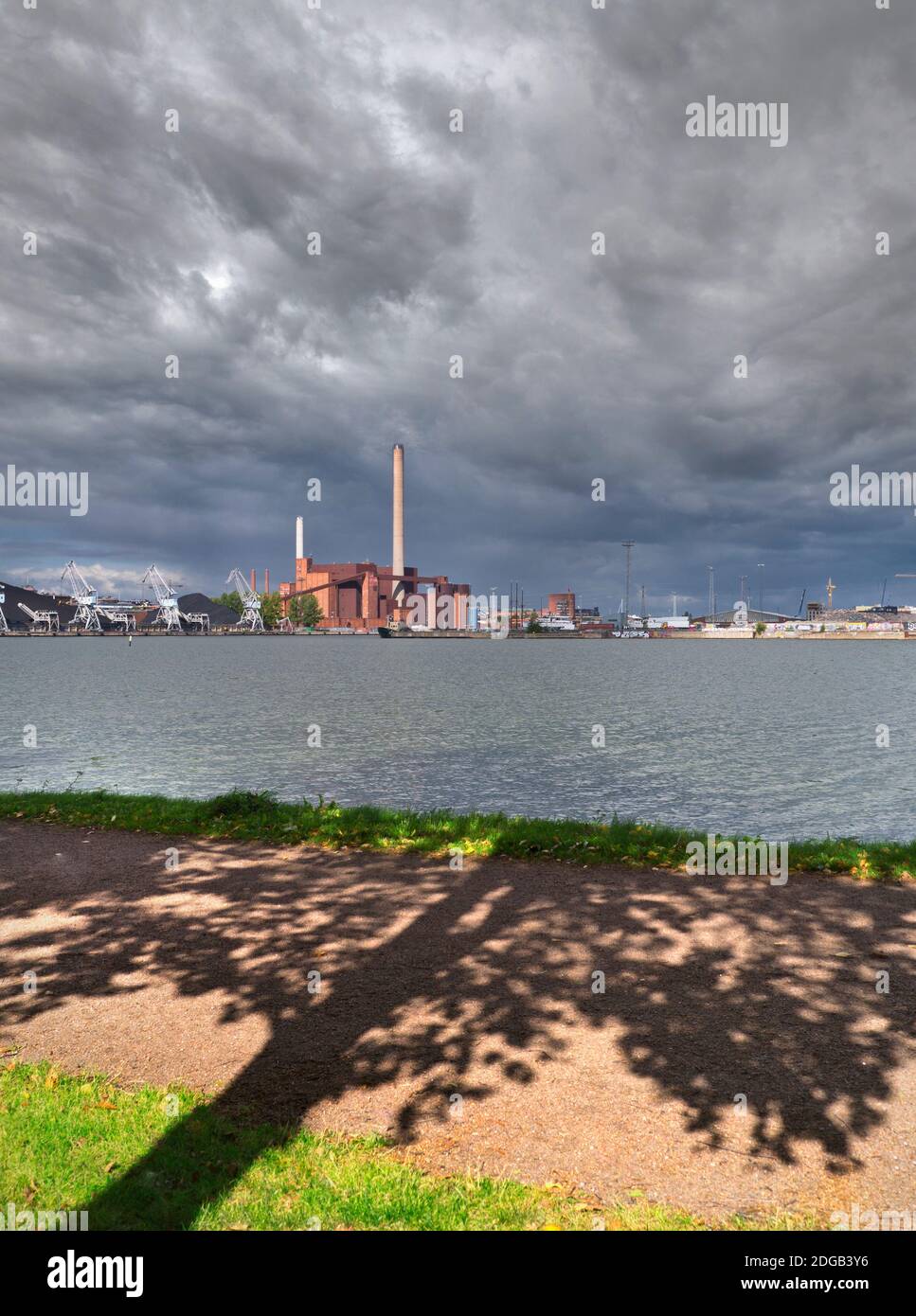 KRAFTWERK Kohlekraftwerk fossile Brennstoffe grünes Konzept Alte Technologie unter konzeptuell dramatischen dunklen brooding Himmel mit Baum Und lässt Silhouetten im Vordergrund, was auf grünere kohlenfreie zukünftige Energie hindeutet Möglichkeiten Stockfoto