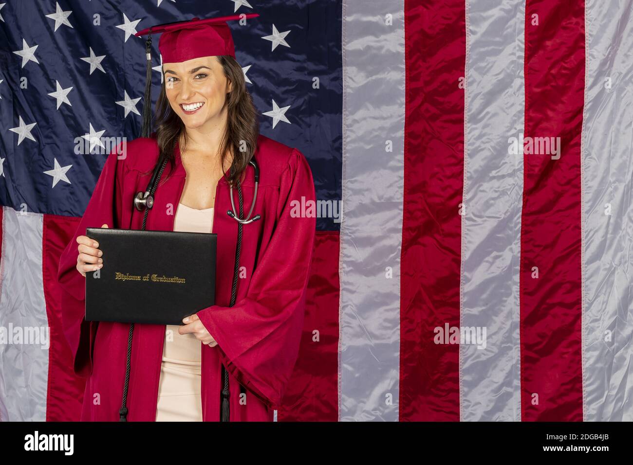 Schöne Brünette Modell posiert mit EINEM Diplom mit einem Amerikaner Flagge Im Hintergrund Stockfoto