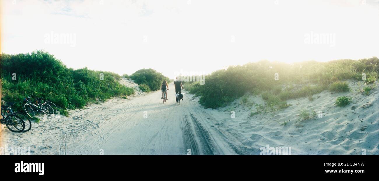 Rückansicht eines Paares, das entlang eines Strandweges radelt, Fort Tilden, Queens, New York City, New York State, USA Stockfoto