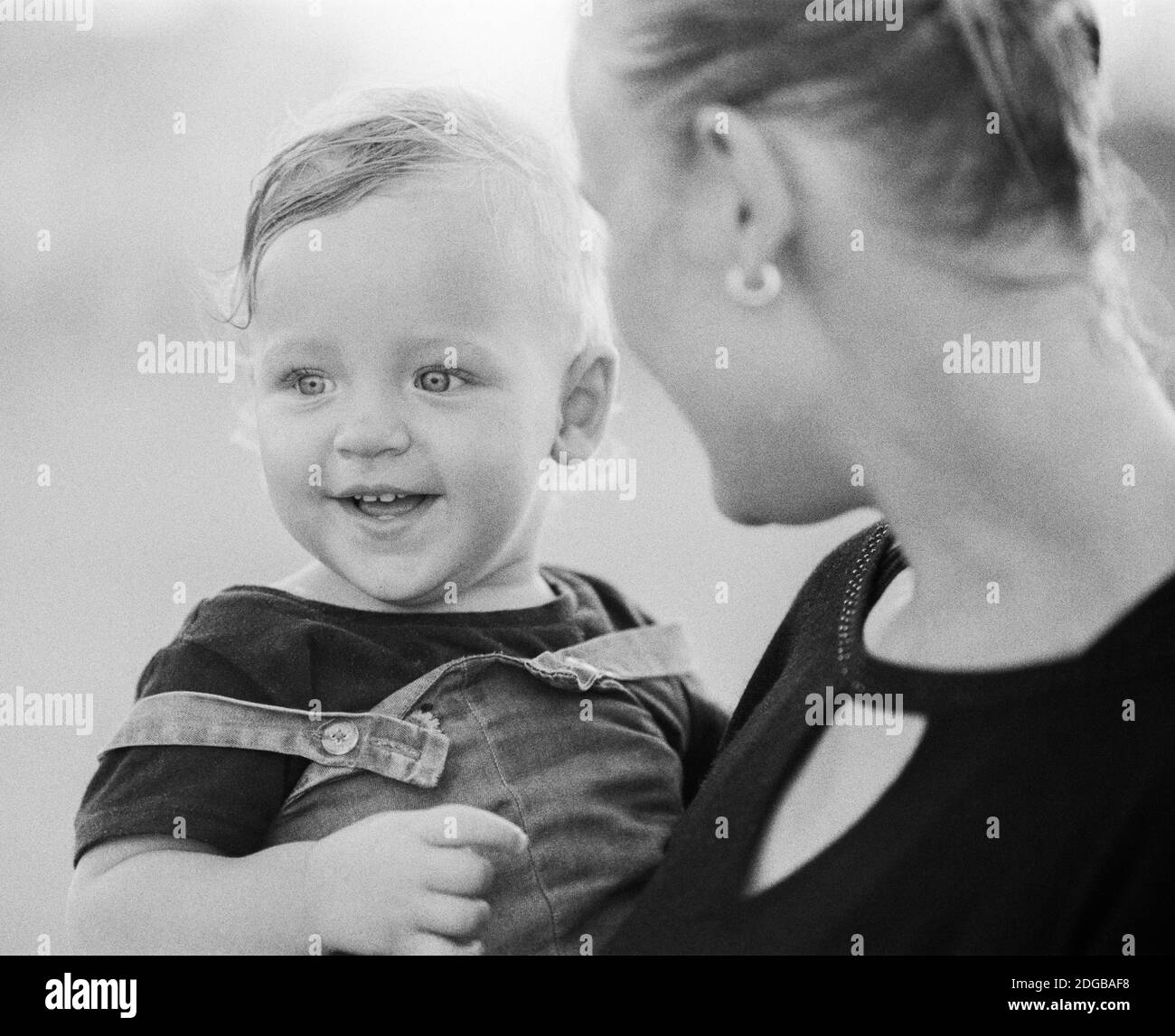 Liebevolle Mutter mit Baby in den Armen. Schwarz und Weiß Stockfoto