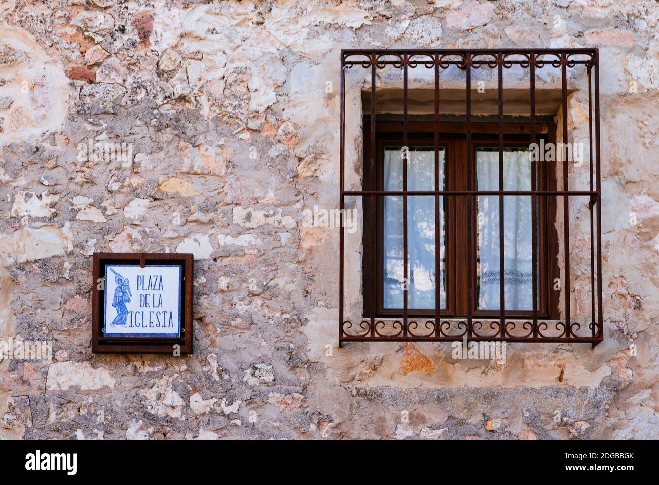Wand eines Hauses mit Fenster von einem schmiedeeisernen Zaun mit Ornamenten eingerahmt. Plaza de la Iglesia - Platz der Kirche. Medinaceli, Soria, Castilla y León, Stockfoto