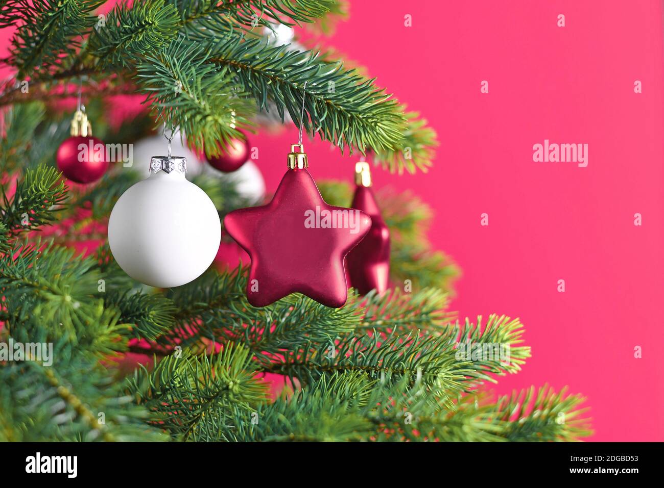 Nahaufnahme von geschmückten Weihnachtsbaum mit rosa Stern geformt Und weiße Kugel formt Baum Ornament Kugeln auf rosa Hintergrund Stockfoto