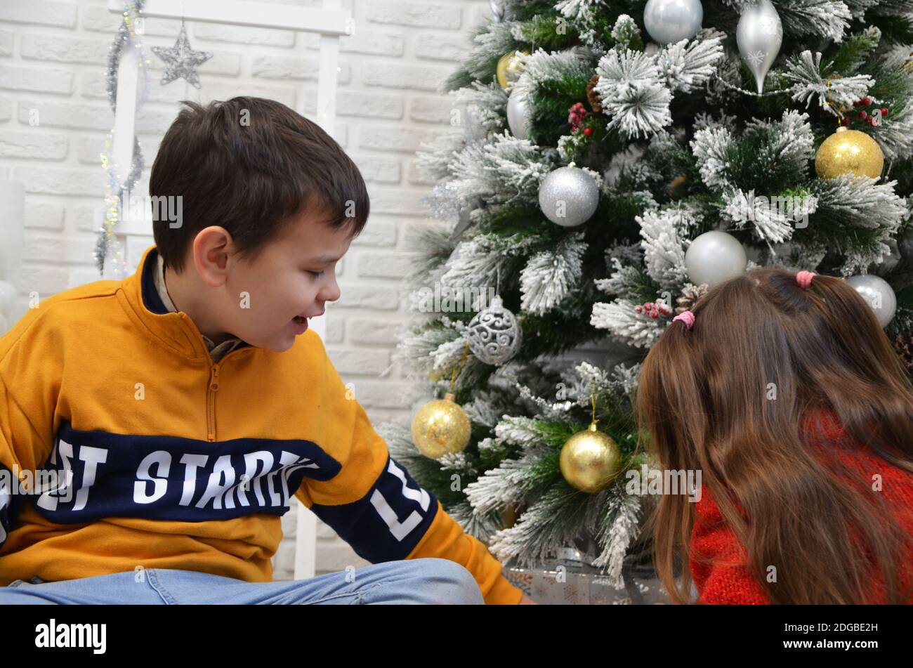 Glückliche kleine Kinder schmücken Weihnachtsbaum in schönen Wohnzimmer mit traditionellen Kamin. Kinder Eröffnung Geschenke am Weihnachtsabend. Offene Geschenke, pla Stockfoto