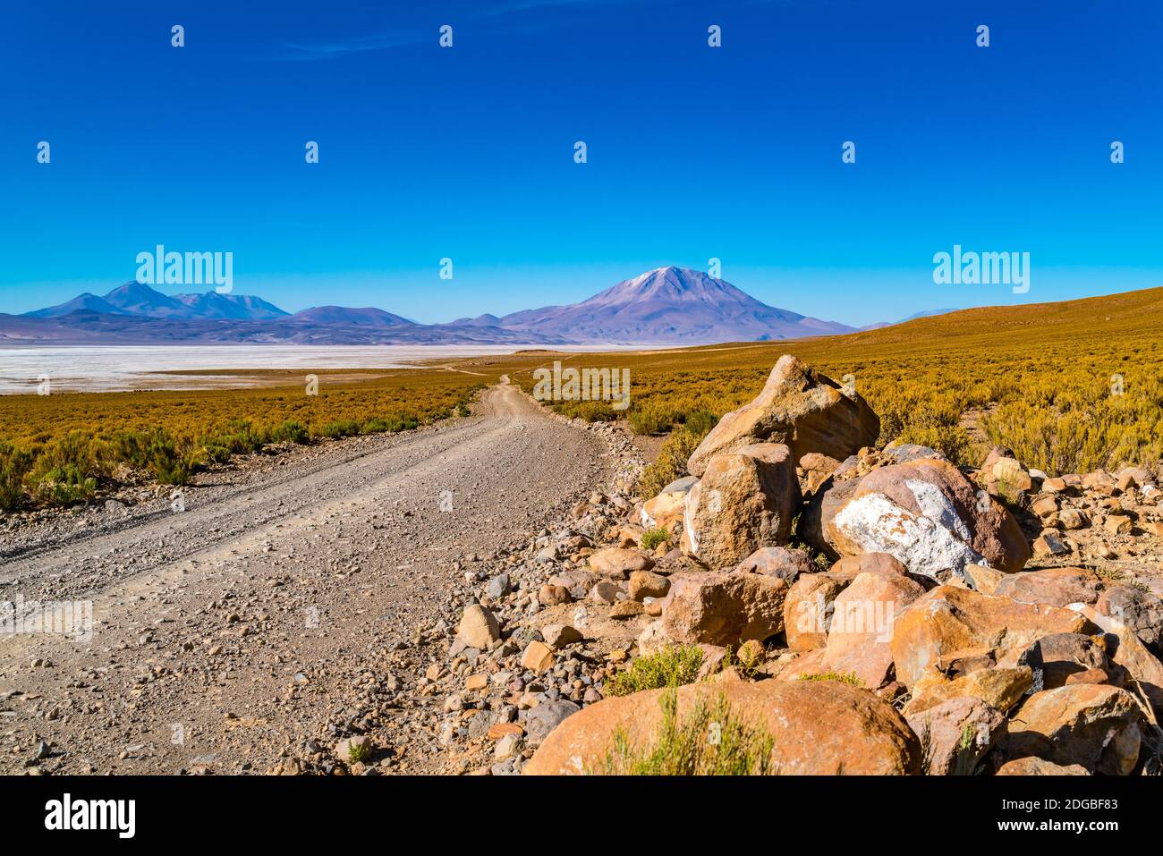 Blick auf Salar de Uyuni mit dem schlafenden Vulkan und Eine schmutzige Straße Stockfoto