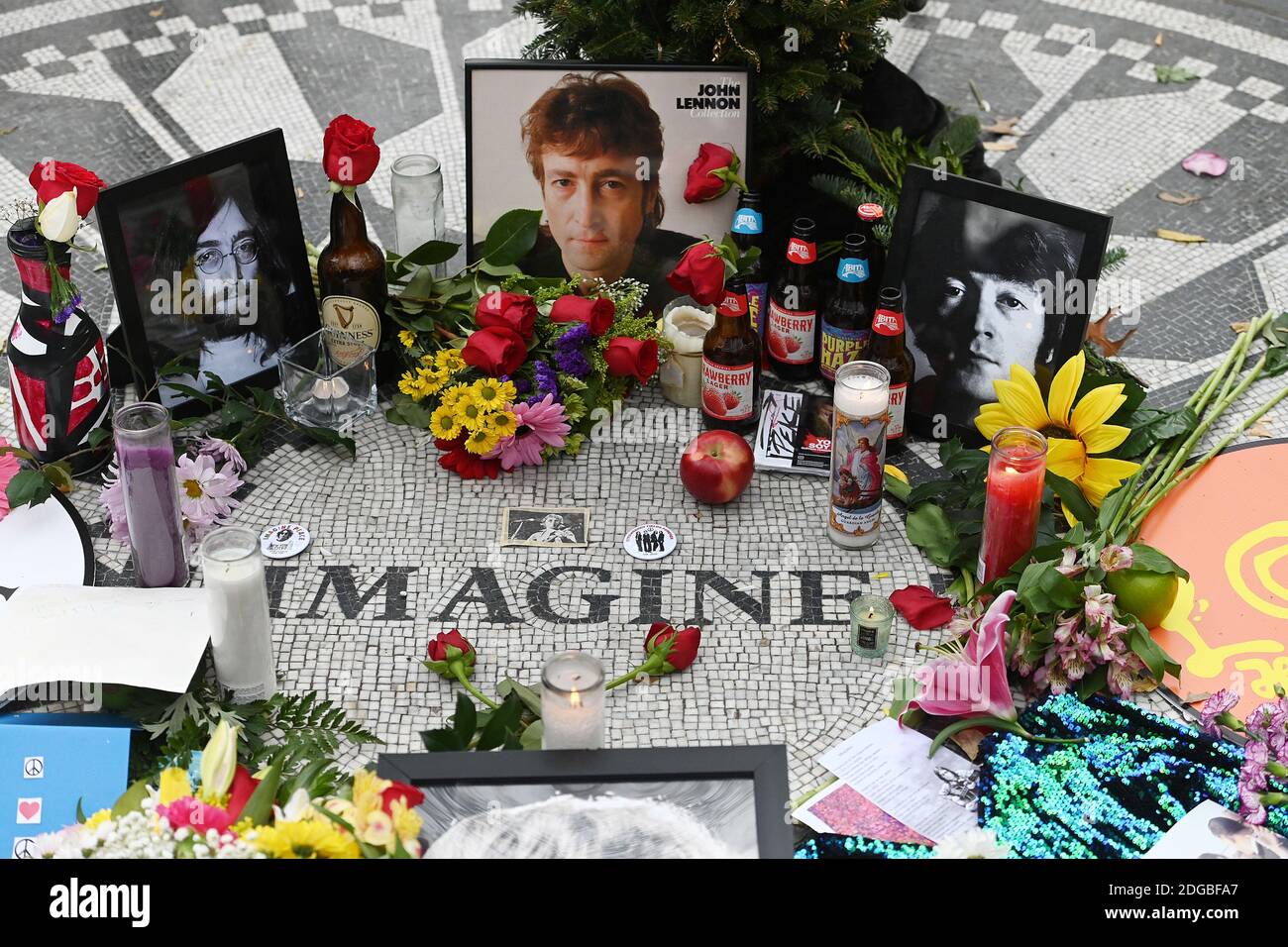 New York, USA. Dezember 2020. Die Menschen legen Blumen und Bilder auf das Imagine Mosaik in Strawberry Fields im Central Park, zum Gedenken an den 40. Todestag des Musikers John Lennon, New York, NY, 8. Dezember 2020. Der ehemalige Beatle wurde am Abend des 8. Dezember 1980 von einem Fan vor seiner Residenz The Dakota auf Manhattans Upper West Side erschossen. (Foto von Anthony Behar/Sipa USA) Quelle: SIPA USA/Alamy Live News Stockfoto