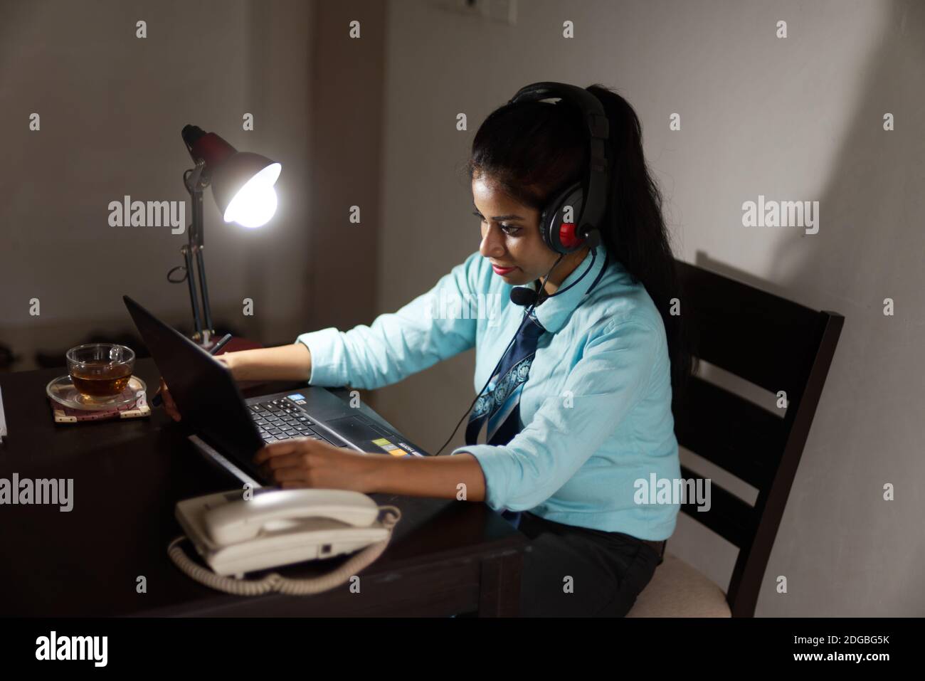 Eine indische bengalische Brünette junge Frau/telecaller in Bürokleidung ist Sitzen auf einem Bürotisch in einer Arbeitsstimmung in Ein Unternehmensbüro/bpo/Call Center Stockfoto