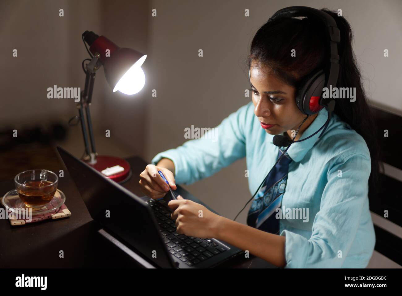 Eine indische bengalische Brünette junge Frau/telecaller in Bürokleidung ist Sitzen auf einem Bürotisch in einer Arbeitsstimmung in Ein Unternehmensbüro/bpo/Call Center Stockfoto