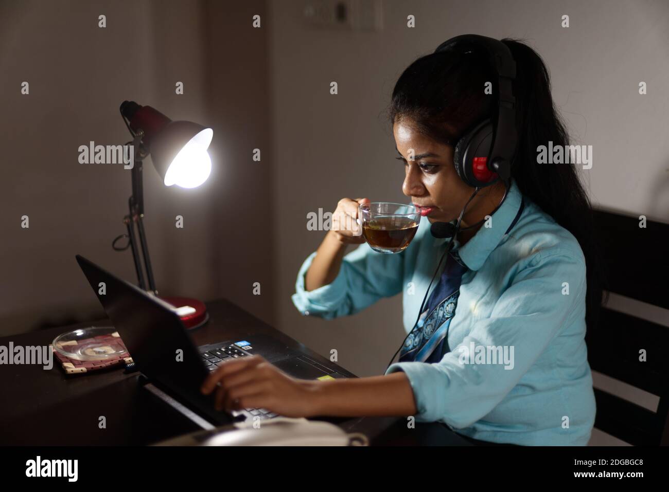 Eine indische bengalische Brünette junge Frau/telecaller in Bürokleidung ist Sitzen auf einem Bürotisch in einer Arbeitsstimmung in Ein Unternehmensbüro/bpo/Call Center Stockfoto