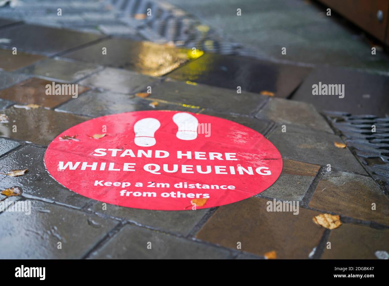 Fußbodenmarkierung für soziale Entfernungen im Stadtzentrum von Großbritannien. Öffentlicher Ratschlag, bei einer Coronavirus-Pandemie einen Abstand von 2m m zu anderen Personen einzuhalten. Stockfoto
