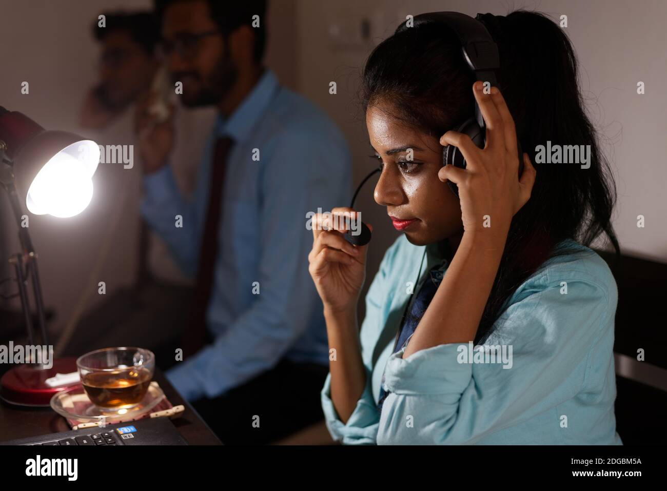 Eine indische bengalische Brünette junge Frau/telecaller in Bürokleidung sitzt auf einem Bürotisch in einer Arbeitsstimmung in einem Firmenbüro / bpo / Call Center. Stockfoto