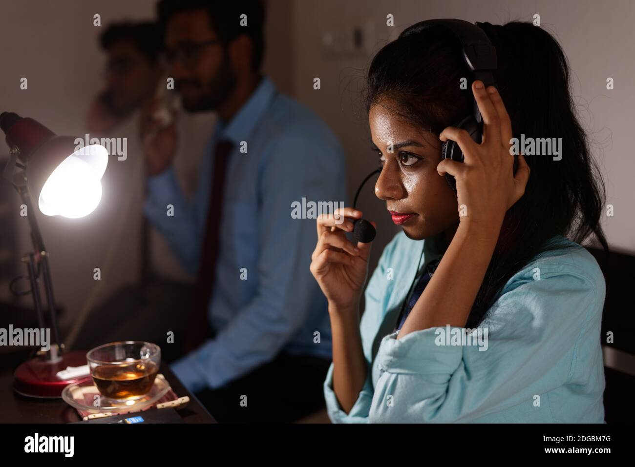 Eine indische bengalische Brünette junge Frau/telecaller in Bürokleidung sitzt auf einem Bürotisch in einer Arbeitsstimmung in einem Firmenbüro / bpo / Call Center. Stockfoto