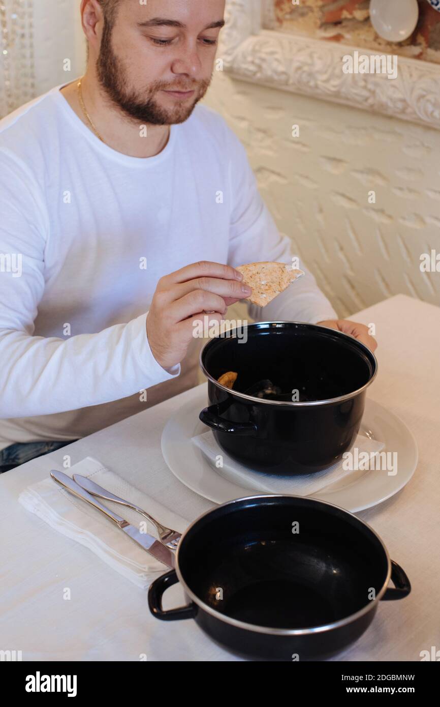 Mann, der gedünstete Muscheln mit einem Stück Brot isst Stockfoto