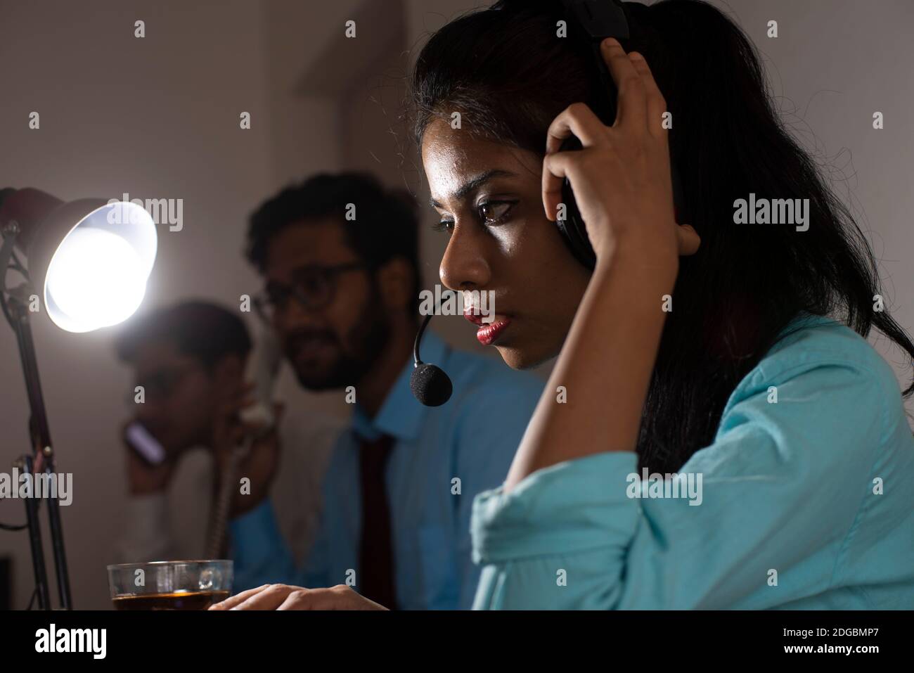 Eine indische bengalische Brünette junge Frau/telecaller in Bürokleidung sitzt auf einem Bürotisch in einer Arbeitsstimmung in einem Firmenbüro / bpo / Call Center. Stockfoto