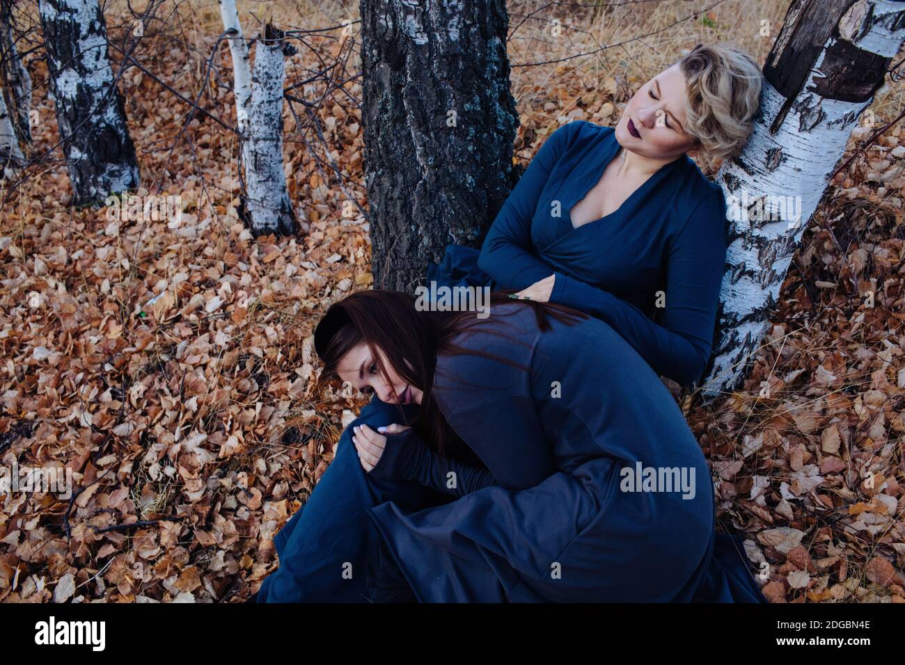 Porträt zweier Frauen, die in einem Wald sitzen und sich an einen Baum lehnen, Russland Stockfoto