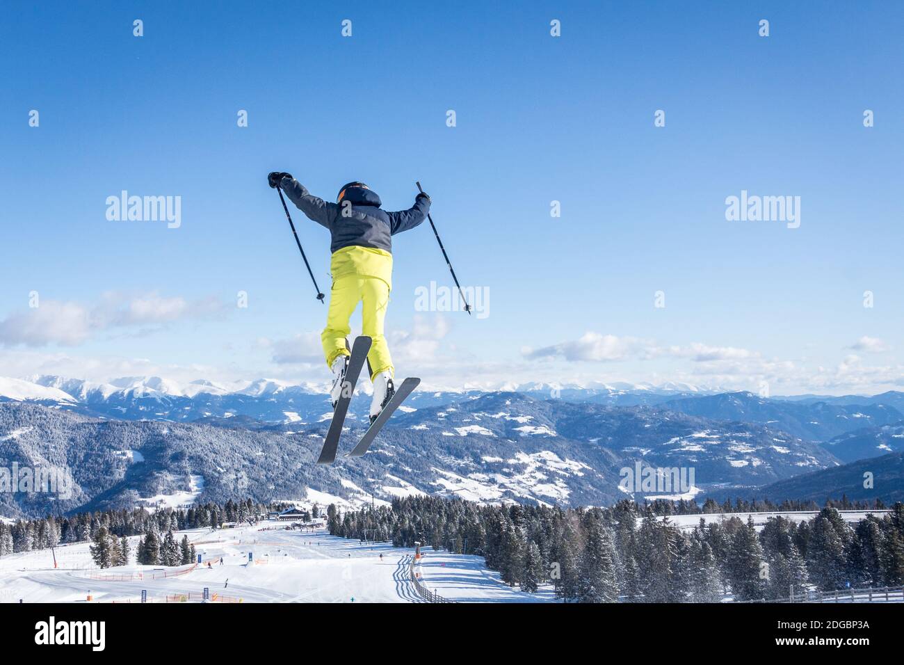 Eine Person, die beim Skifahren auf einem verschneiten Gebiet umringt springt Durch Hügel unter dem Sonnenlicht Stockfoto
