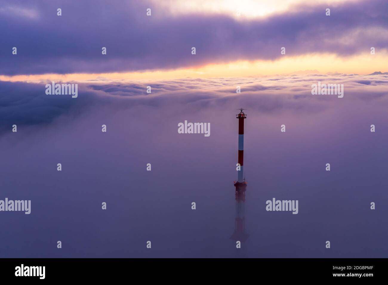 Kommunikationsturm, der bei Sonnenaufgang durch einen Wolkenteppich steigt, Salzburg, Österreich Stockfoto