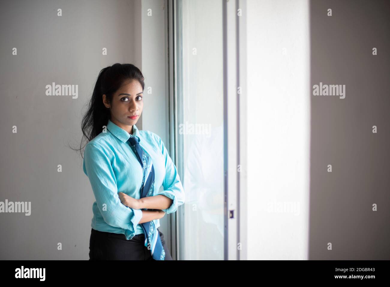 Indische Bengali attraktive Brünette junge Frau im Büro tragen vor einem Fenster in einem Firmenbüro / bpo / Call Center stehen. Stockfoto