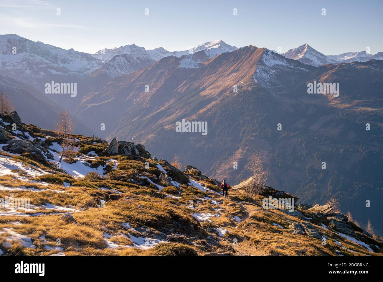 Frau Mountainbiken in der alpinen Landschaft im Spätherbst Schnee, Gastein, Salzburg, Österreich Stockfoto