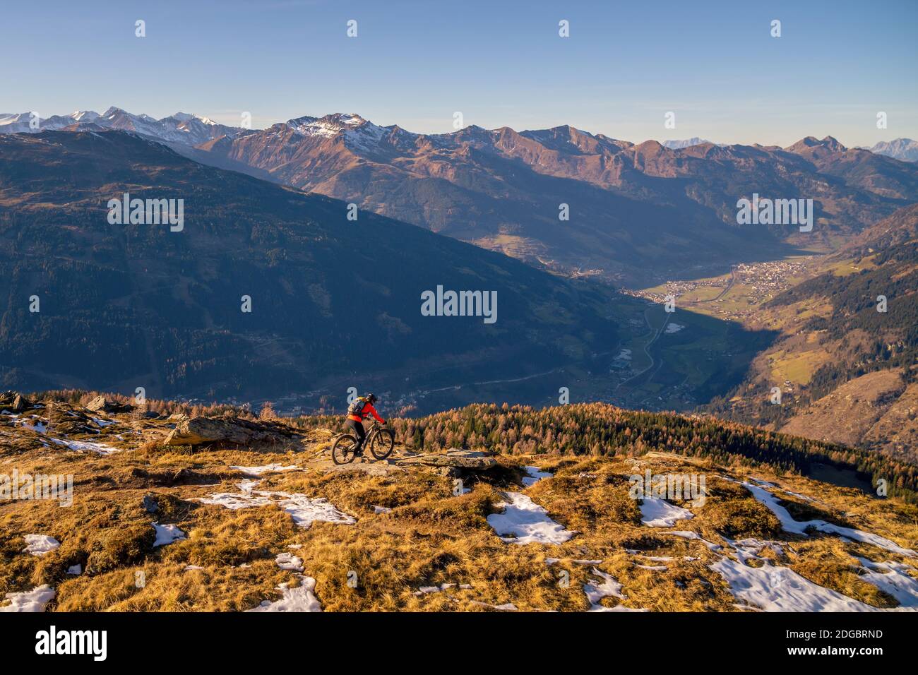 Frau Mountainbiken in der alpinen Landschaft im Spätherbst Schnee, Gastein, Salzburg, Österreich Stockfoto
