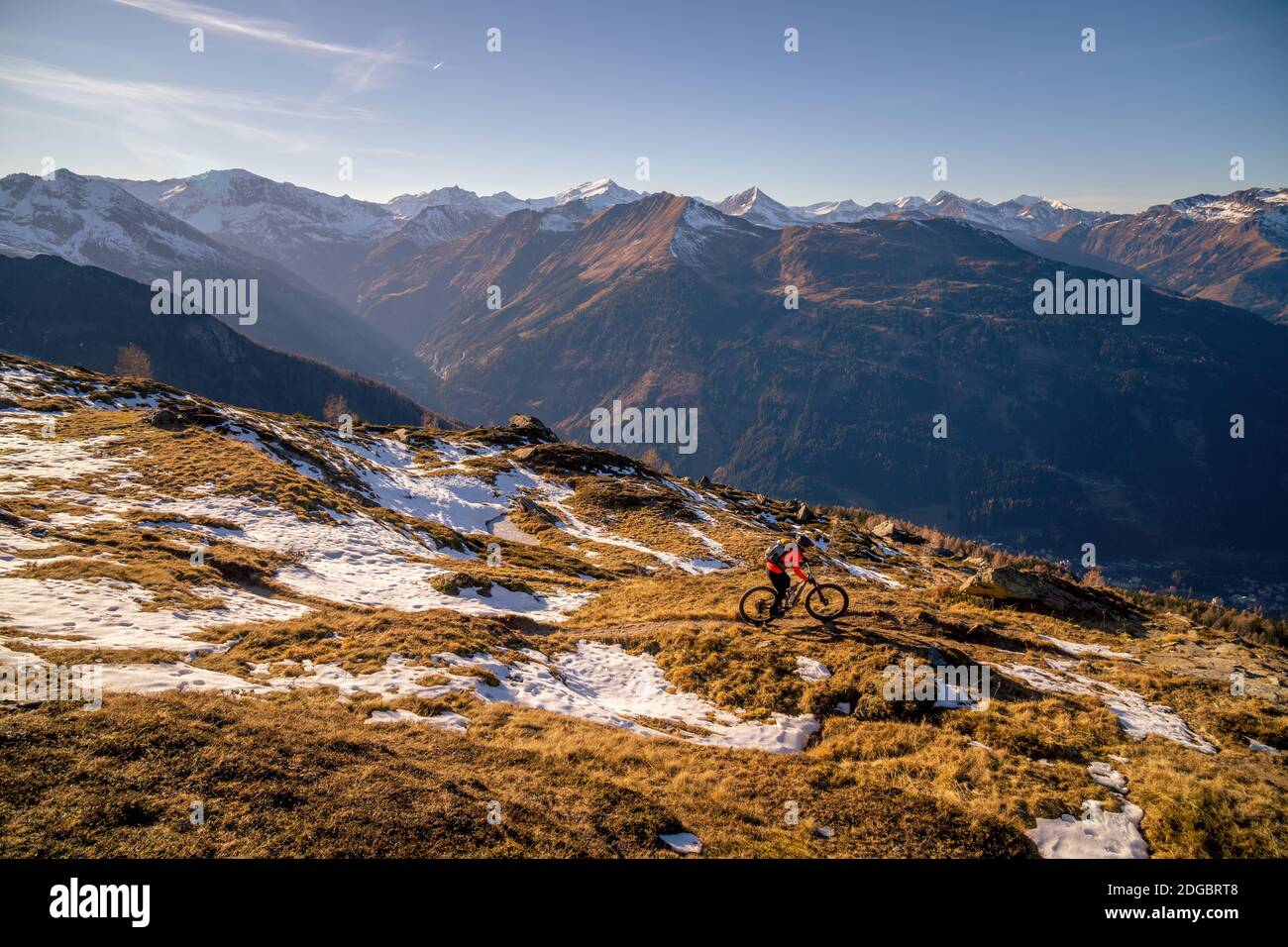 Frau Mountainbiken in der alpinen Landschaft im Spätherbst Schnee, Gastein, Salzburg, Österreich Stockfoto