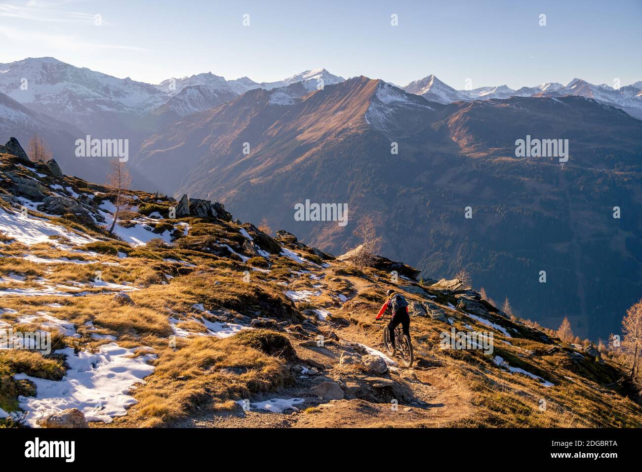 Frau Mountainbiken in der alpinen Landschaft im Spätherbst Schnee, Gastein, Salzburg, Österreich Stockfoto