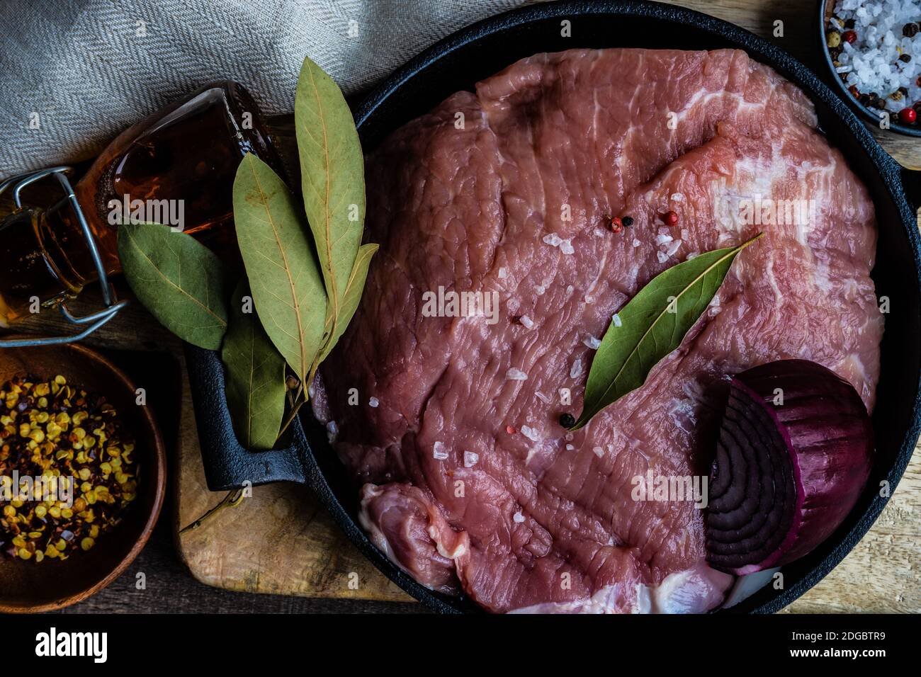 Schweinefleisch in einem Topf mit roten Zwiebeln, Lorbeerblättern, Chili und Salz Stockfoto