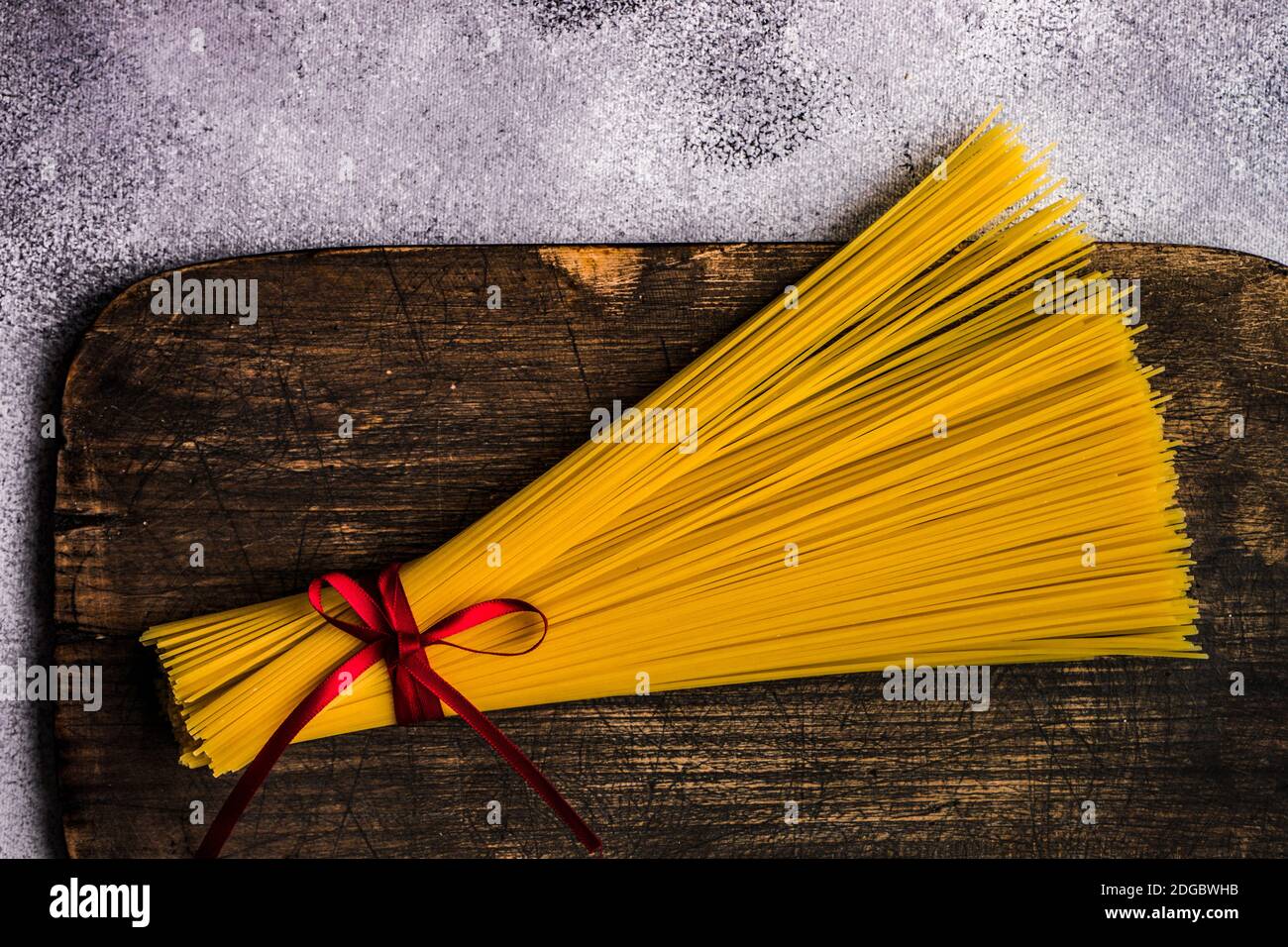 Bündel von rohen Spaghetti mit einem Band auf einem gebunden Schneidebrett Stockfoto