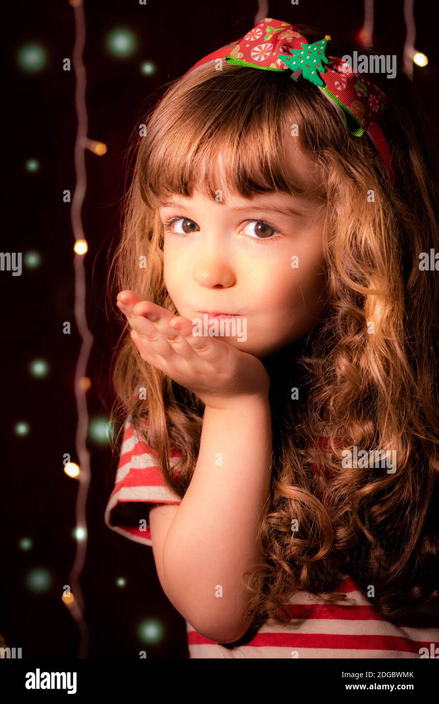 Porträt eines lächelnden Mädchen weht Küsse vor Weihnachtsbeleuchtung Stockfoto
