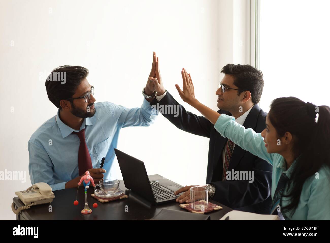 Junge und tatkräftige indische bengalische Unternehmensmitarbeiter feiern Erfolg und Teamarbeit durch Handgesten. Indisches Unternehmen Stockfoto