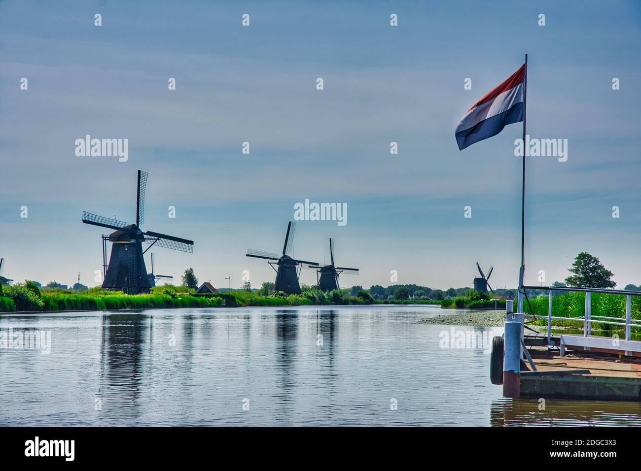 Berühmte holländische Windmühlen am Flussufer mit holländischer Flagge Stockfoto