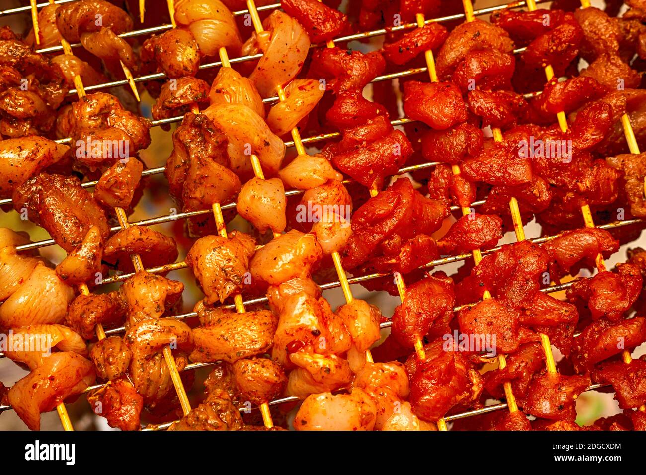 Muster aus buntem Hühnchen- und Schweinefleisch-Schaschlik mit Curry gewürzt Und Paprika würzig lecker aufgereiht o Stockfoto