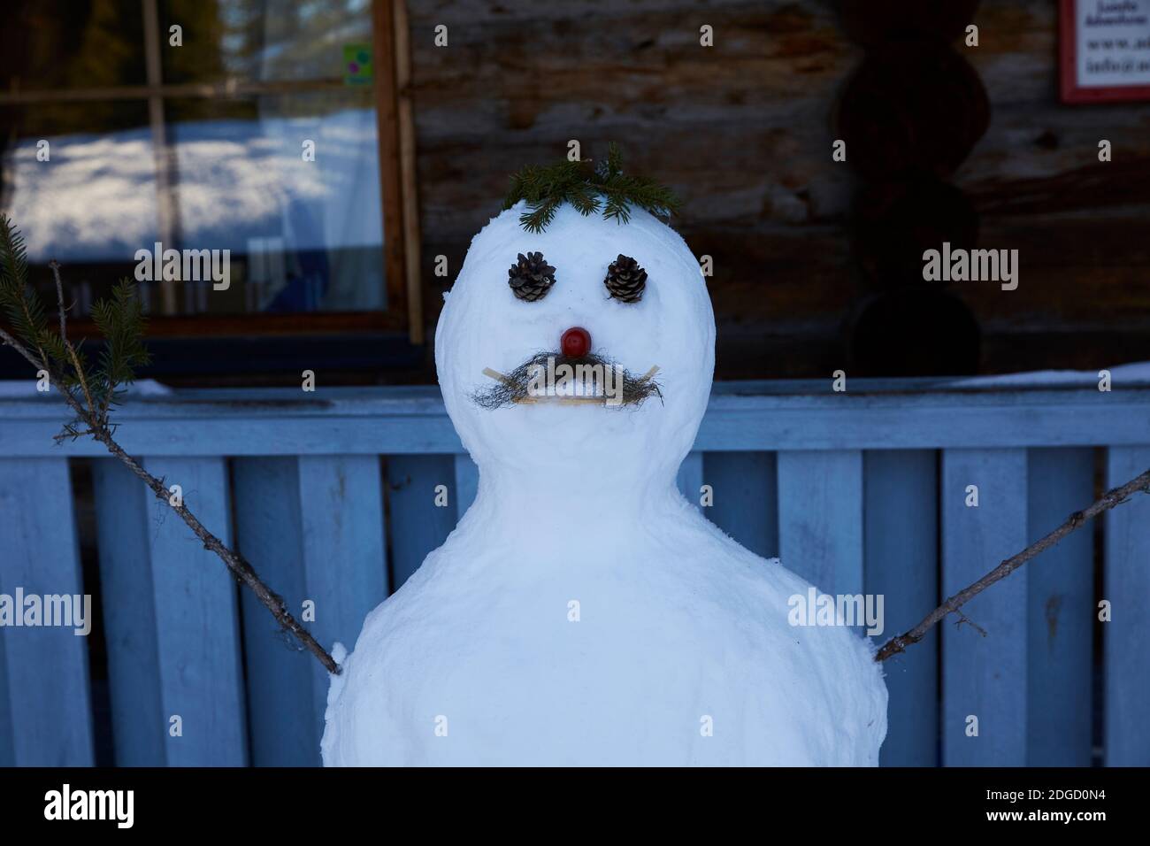 Schneemann mit Schnurrbart vor der Blockhütte in Lappland, Polarkreis, Finnland Stockfoto