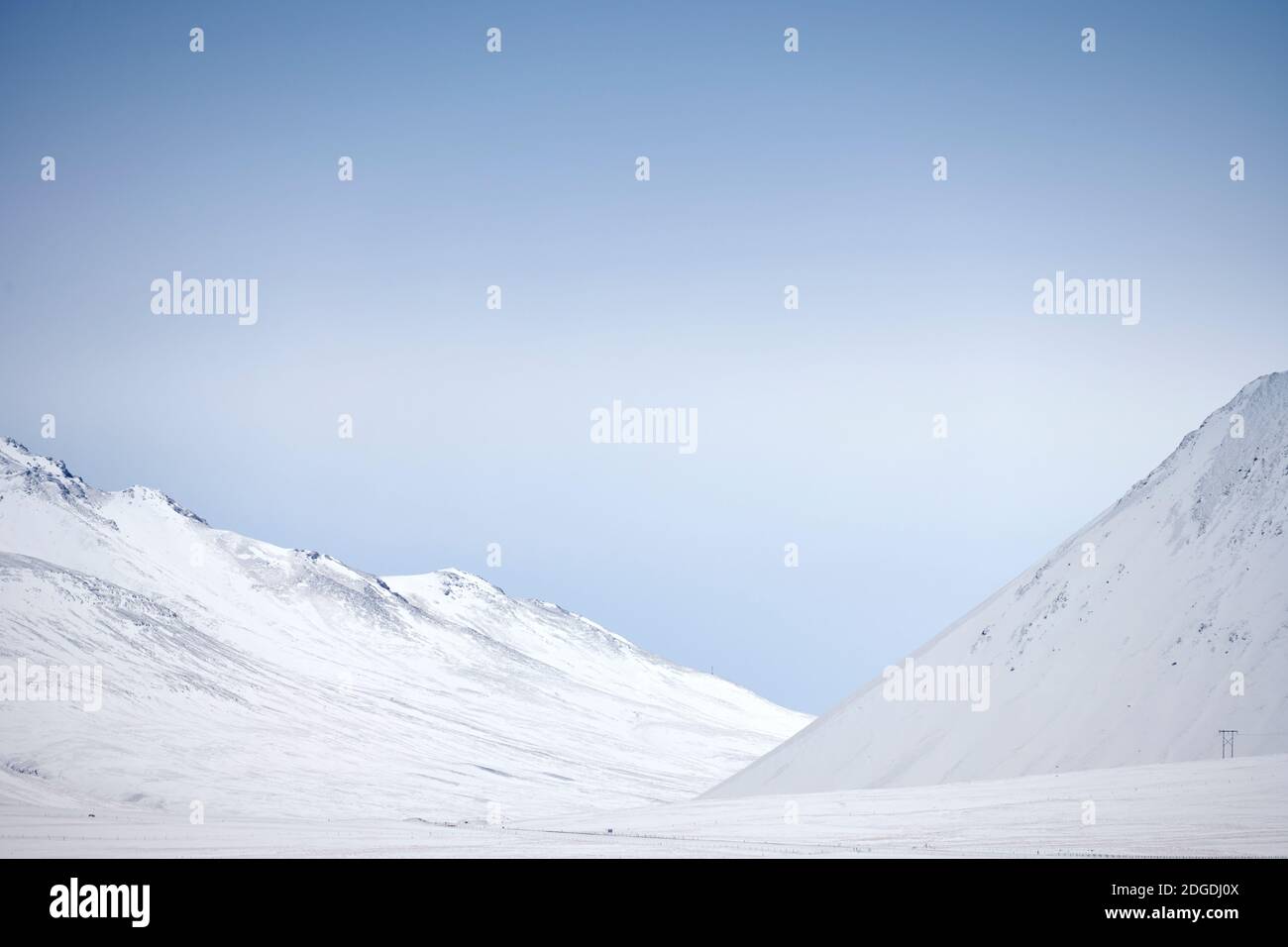 Minimalistische nördliche Landschaft von weißen schneebedeckten Berghängen und Blauer Himmel Stockfoto